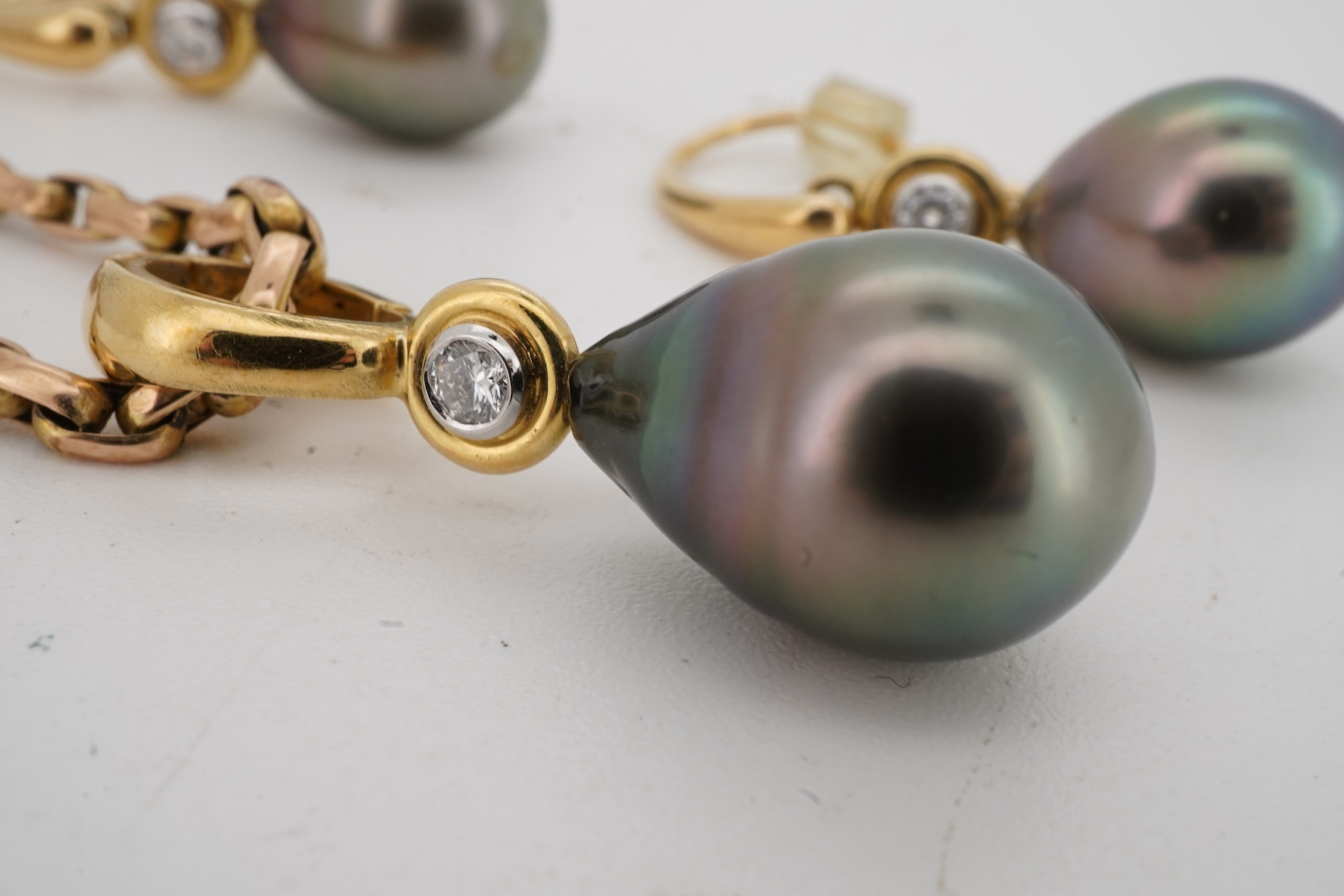 A cultured pearl and diamond demi-parure, comprising: a pendant, suspending a drop-shaped cultured pearl of black tint, measuring approximately 15 x 10.5 x 10.5mm, surmounted by a collet-set brilliant-cut diamond weighin